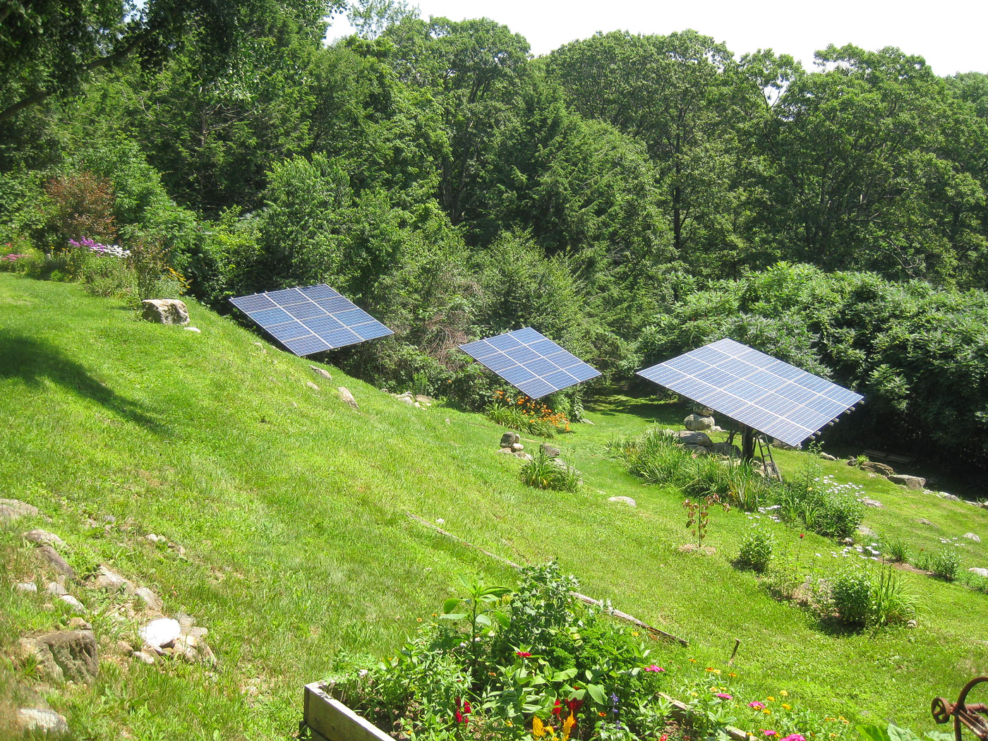 three solar pole mount arrays on a green hillside