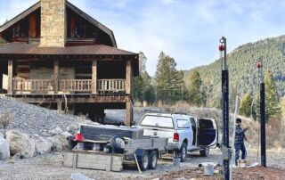 solar installer setting chain hoist with cabin and mountain in background