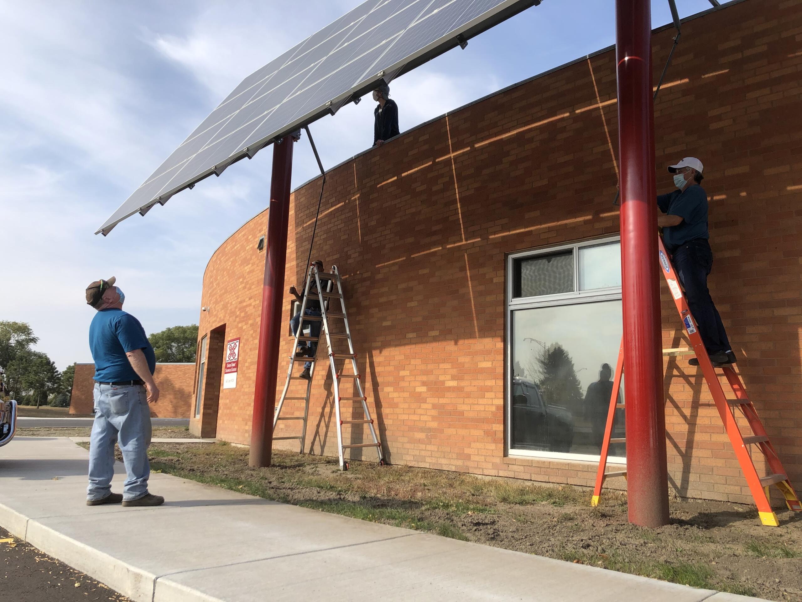 A skilled installation crew uses ladders to ascend and secure the critical components of a solar panel installation